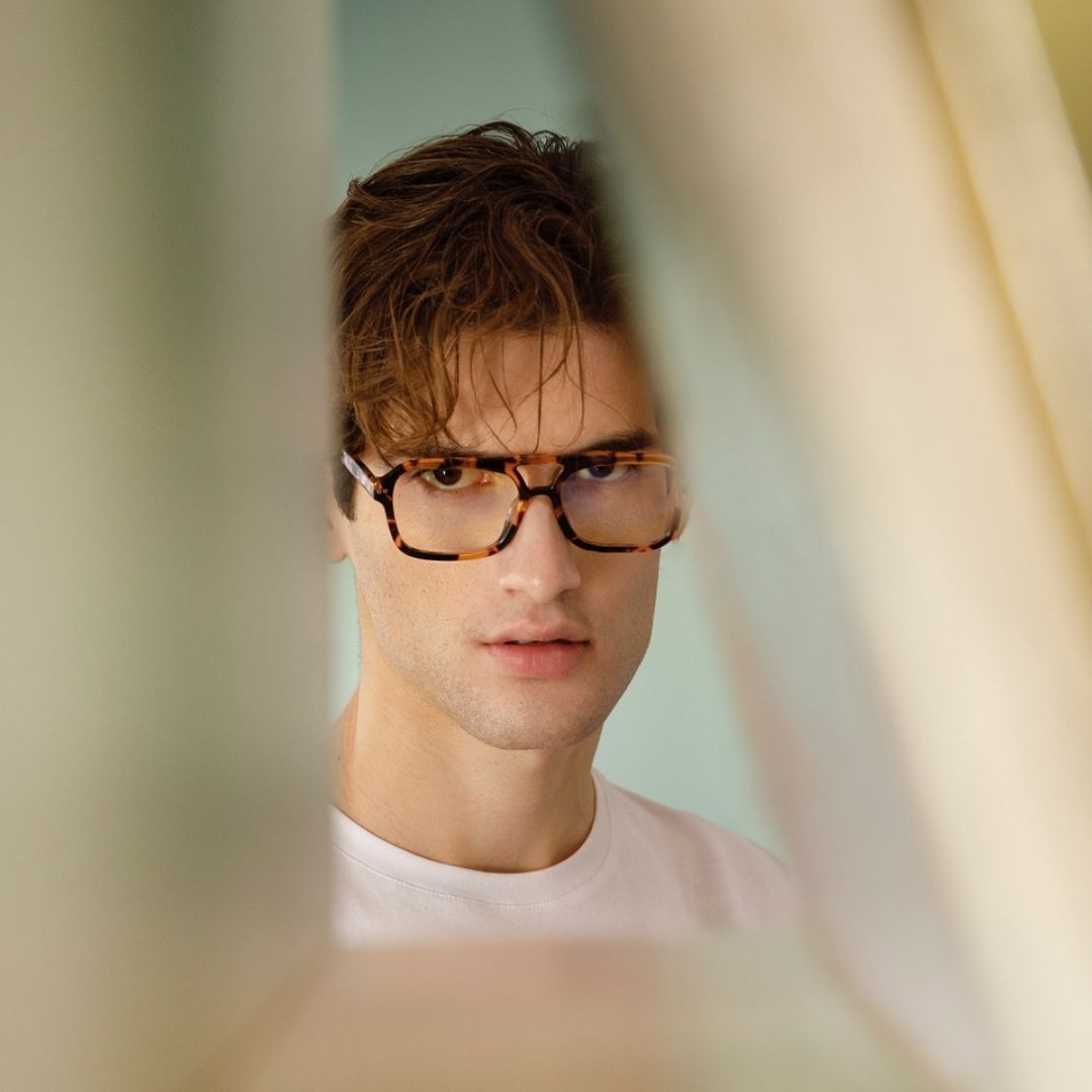 a young man wearing glasses and a tie 
