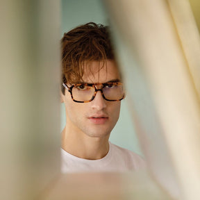 a young man wearing glasses and a tie 